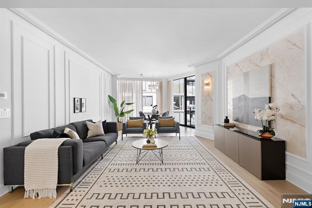 living area featuring floor to ceiling windows, a decorative wall, and light wood-style flooring