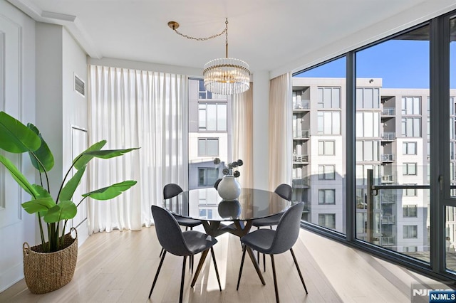 dining space with wood finished floors, visible vents, and an inviting chandelier