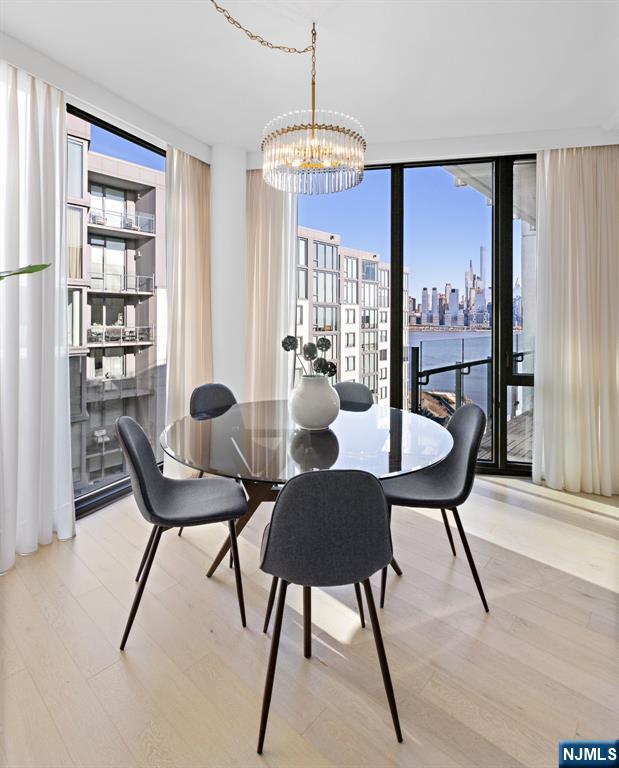 dining space featuring an inviting chandelier, a view of city, floor to ceiling windows, and wood finished floors