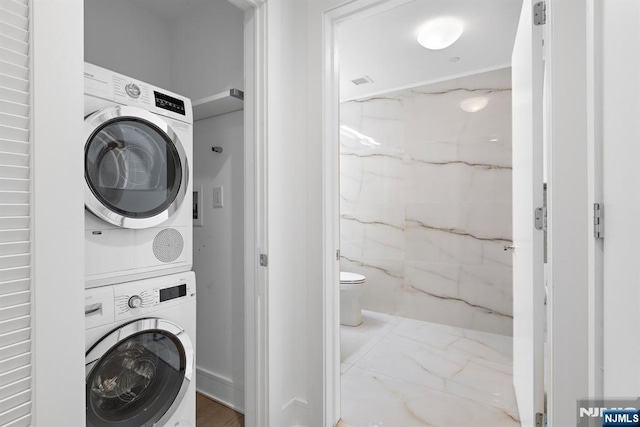 laundry room featuring marble finish floor, laundry area, and stacked washer and clothes dryer