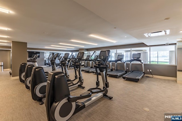 exercise room with baseboards and light colored carpet