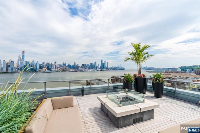 wooden deck with a water view, an outdoor fire pit, and a view of city