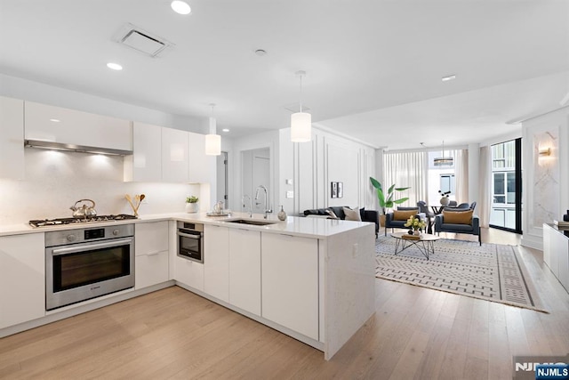 kitchen featuring light wood finished floors, visible vents, modern cabinets, appliances with stainless steel finishes, and a sink