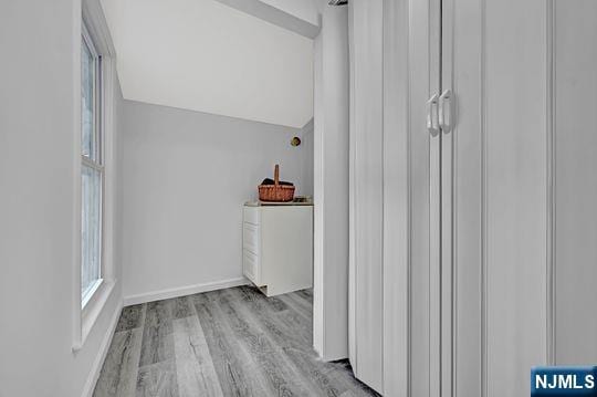 clothes washing area featuring baseboards and wood finished floors