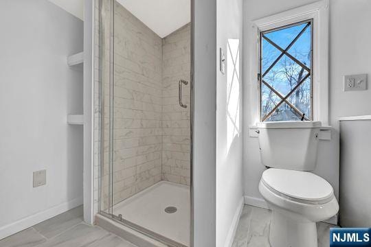 bathroom featuring a stall shower, marble finish floor, toilet, and baseboards