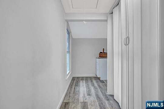 corridor featuring attic access, baseboards, and wood finished floors