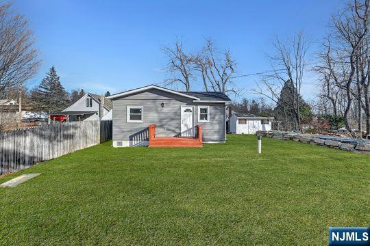 rear view of house with fence and a yard