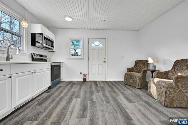 kitchen with appliances with stainless steel finishes, dark wood-type flooring, light countertops, white cabinetry, and a sink