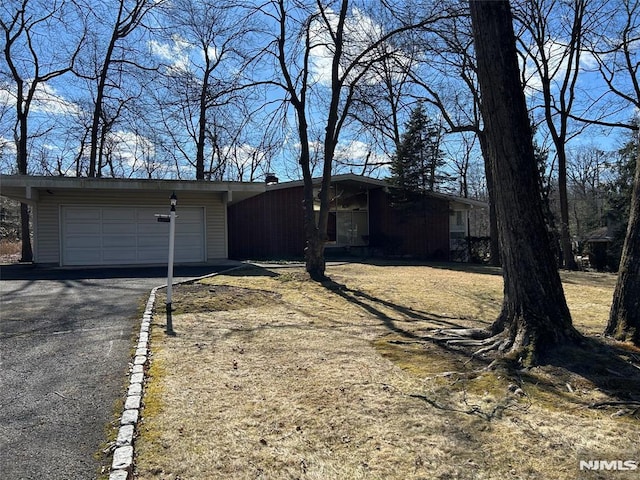 view of front facade featuring driveway, a chimney, and an attached garage