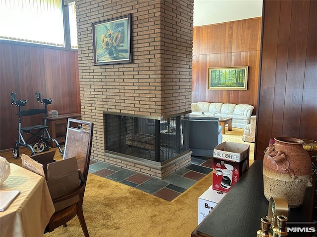 living area with a fireplace, wood walls, and carpet flooring