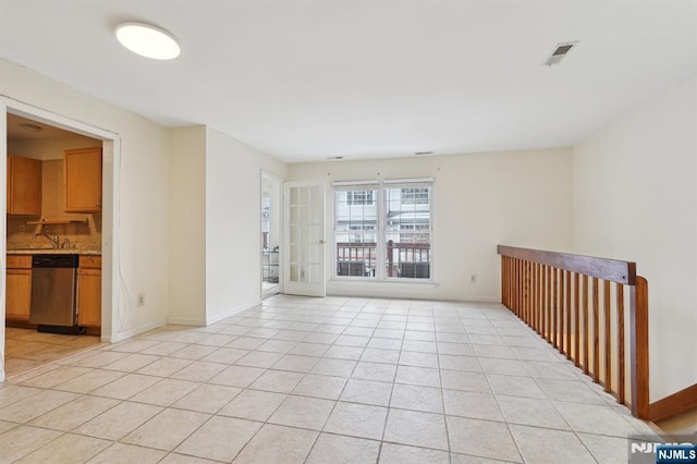 spare room featuring light tile patterned floors, baseboards, visible vents, and a sink