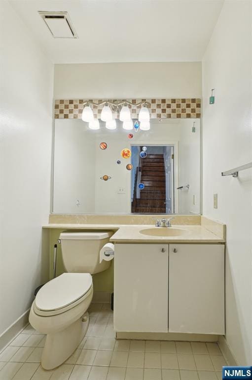 half bath featuring tile patterned flooring, toilet, vanity, visible vents, and baseboards