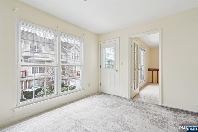 carpeted spare room with a wealth of natural light and tile patterned flooring