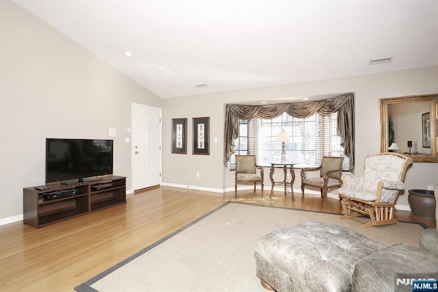 living area featuring vaulted ceiling, wood finished floors, visible vents, and baseboards