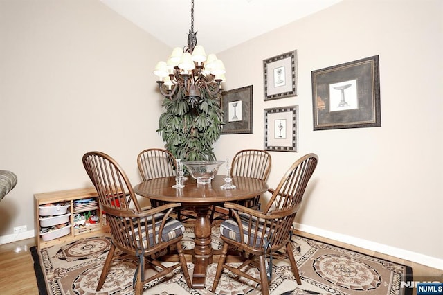 dining room with a chandelier, vaulted ceiling, baseboards, and wood finished floors