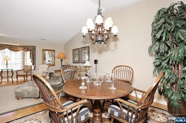 dining room featuring lofted ceiling, an inviting chandelier, baseboards, and wood finished floors