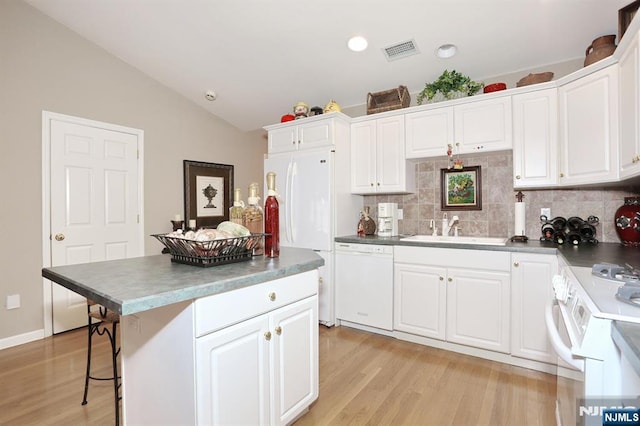 kitchen featuring visible vents, white cabinetry, vaulted ceiling, a sink, and white appliances