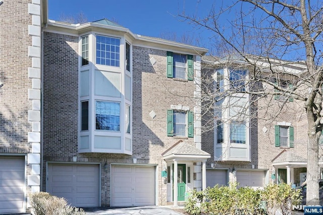 multi unit property with an attached garage and brick siding