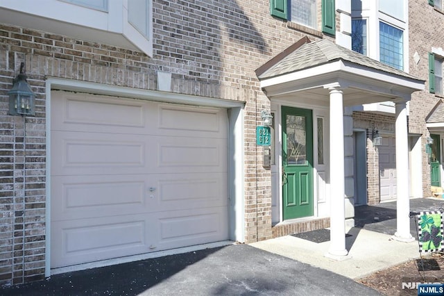 doorway to property featuring a garage and brick siding