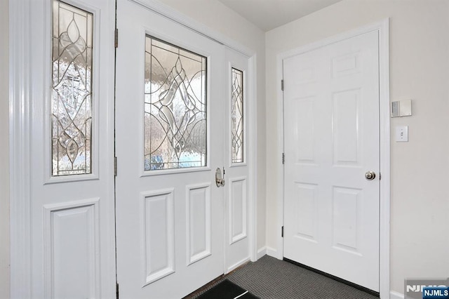 entrance foyer featuring dark colored carpet and baseboards