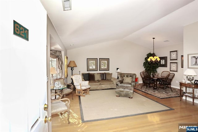 living area with light wood-type flooring, lofted ceiling, visible vents, and a notable chandelier