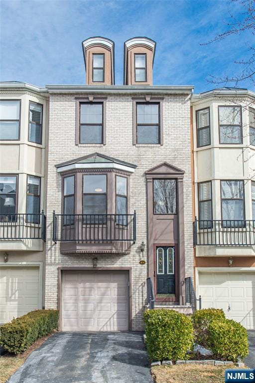 townhome / multi-family property featuring an attached garage, driveway, and brick siding