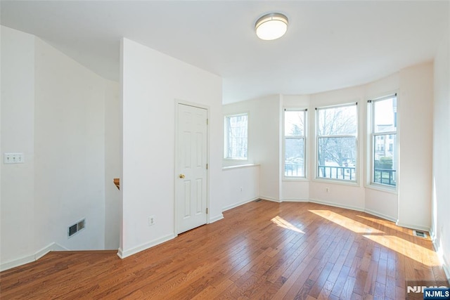 spare room featuring hardwood / wood-style flooring, baseboards, and visible vents