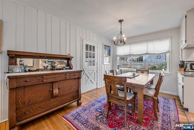 dining space featuring light wood-type flooring and a notable chandelier