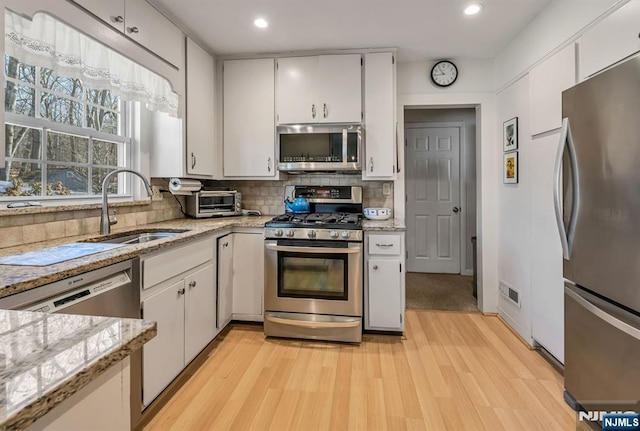 kitchen with stainless steel appliances, tasteful backsplash, a sink, and visible vents