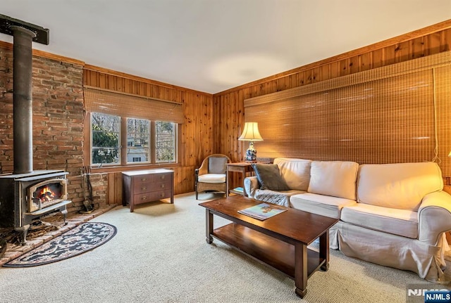 carpeted living room with a wood stove and wood walls