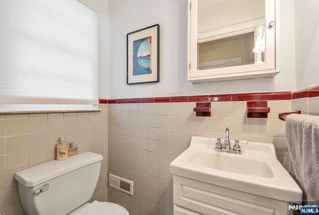 half bathroom with toilet, tile walls, and vanity