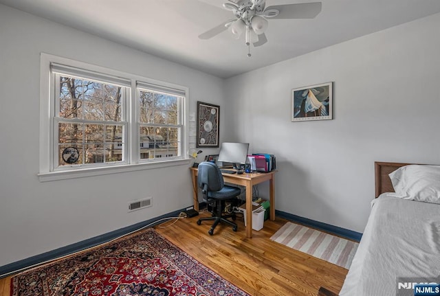 office featuring a ceiling fan, wood finished floors, visible vents, and baseboards