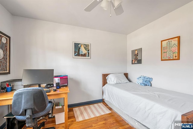 bedroom with a ceiling fan, baseboards, and wood finished floors