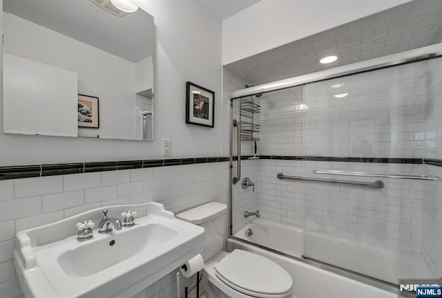 bathroom with toilet, visible vents, bath / shower combo with glass door, and a sink