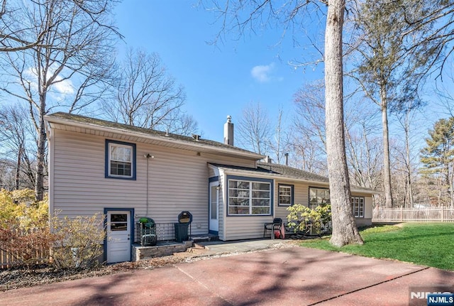 view of front of house with a front lawn, a chimney, a patio area, and fence