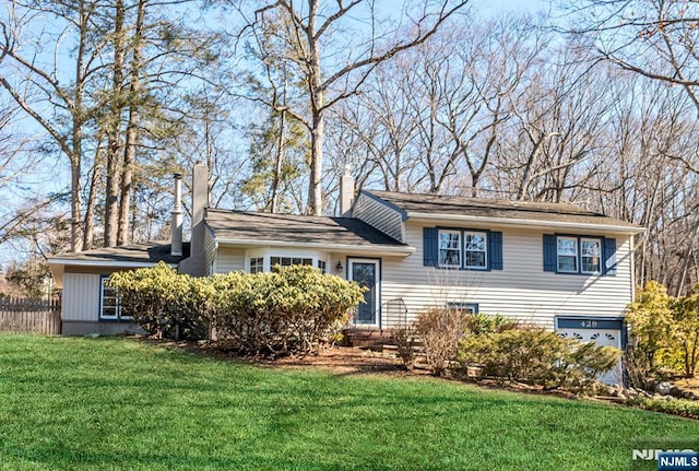 split level home with a front lawn, a chimney, and fence