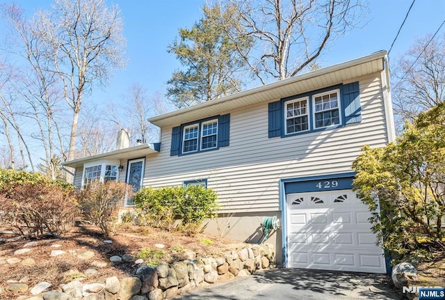 tri-level home with aphalt driveway and an attached garage