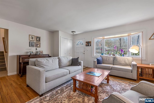 living room featuring hardwood / wood-style flooring, stairs, and baseboards