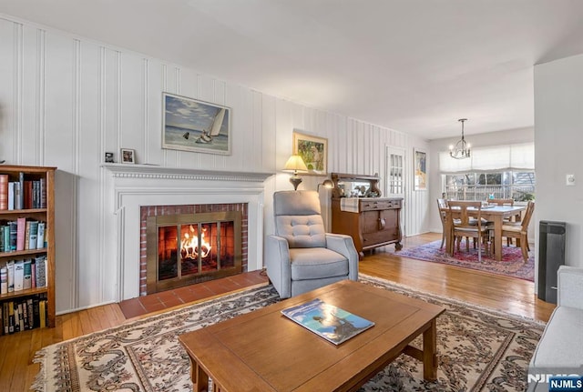 living room featuring a chandelier, wood-type flooring, and a fireplace