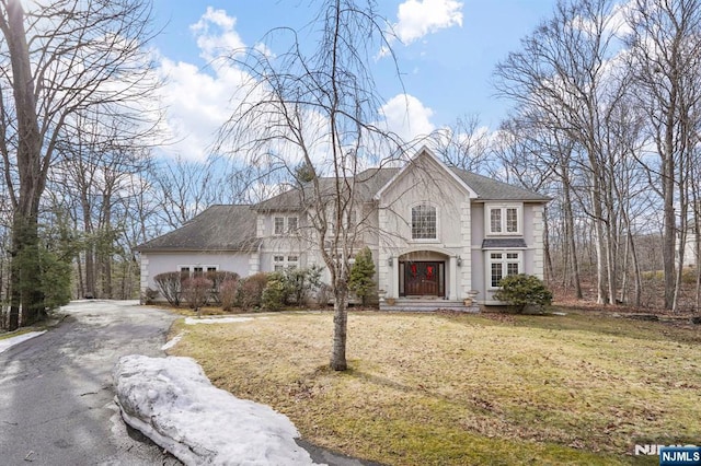 view of front of property with aphalt driveway, a front yard, and stucco siding