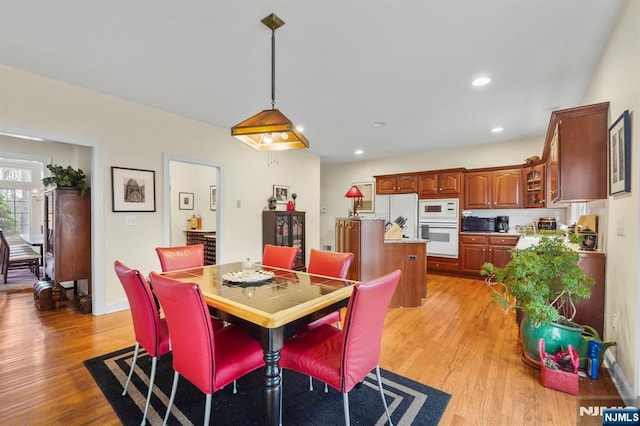 dining area with baseboards, light wood finished floors, and recessed lighting