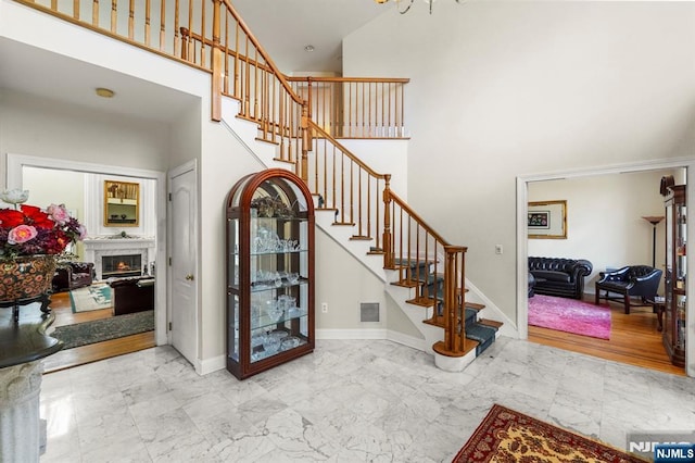 entryway with baseboards, visible vents, a towering ceiling, marble finish floor, and stairs