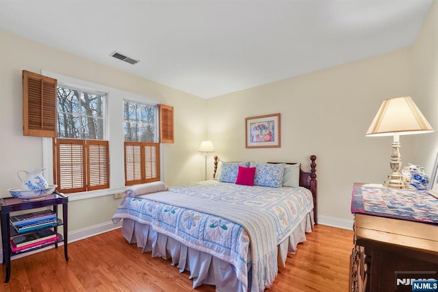 bedroom with baseboards, visible vents, and wood finished floors