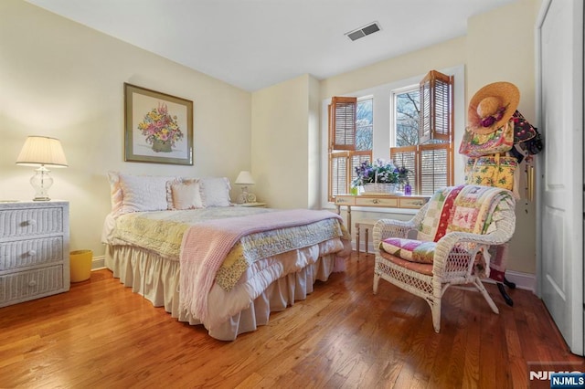 bedroom with visible vents, baseboards, and wood finished floors