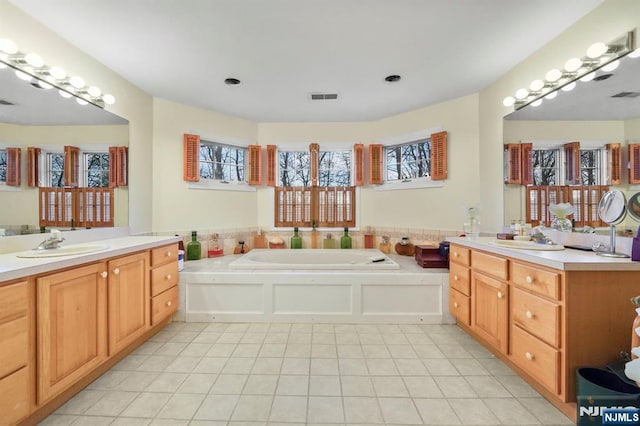 bathroom with tile patterned flooring, visible vents, a sink, and a garden tub