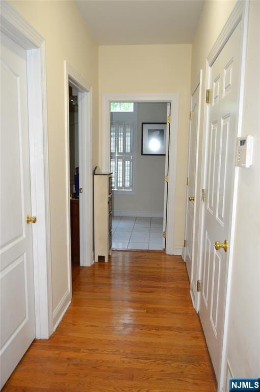 hallway featuring light wood-type flooring and baseboards