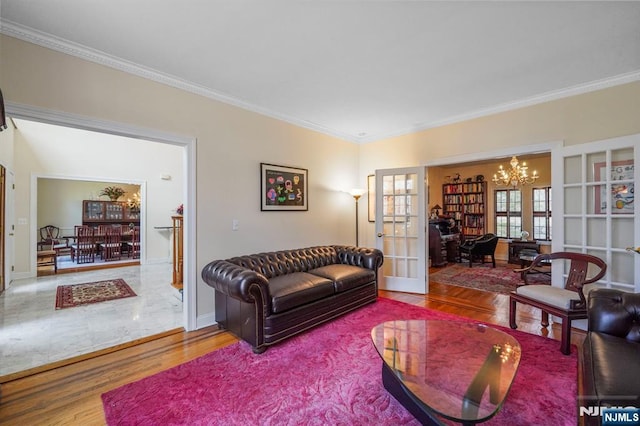 living area with french doors, crown molding, an inviting chandelier, wood finished floors, and baseboards