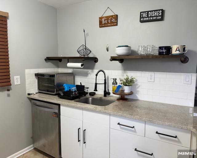 kitchen with light stone counters, open shelves, decorative backsplash, a sink, and dishwasher