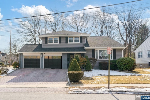 view of front of home featuring decorative driveway, brick siding, and roof with shingles