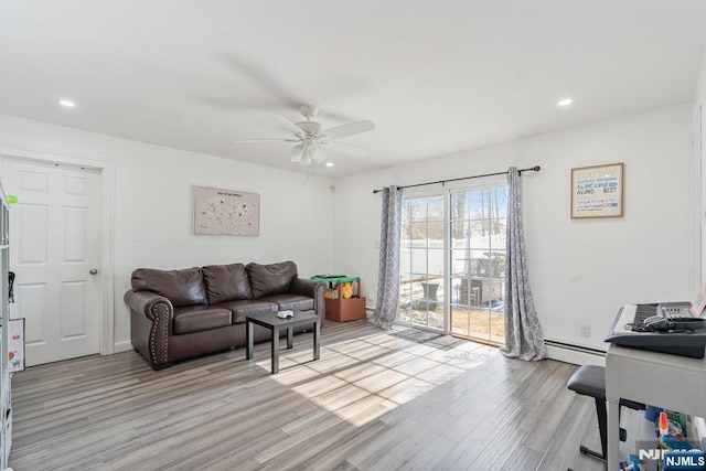 living room featuring baseboard heating, light wood-type flooring, a ceiling fan, and recessed lighting